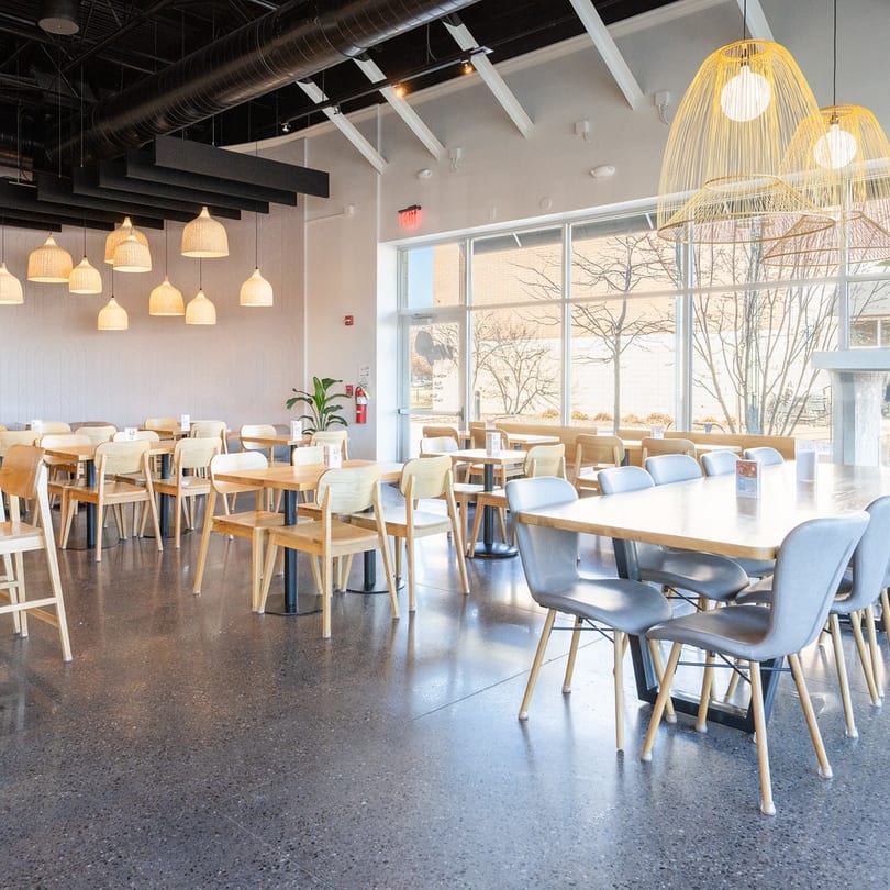 Bright, modern Up Leaf Café interior with light wood tables, gray chairs, and large windows.